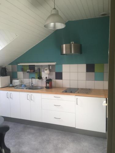 uma cozinha com armários brancos e uma parede azul em Appartement cosy et lumineux em Nantes