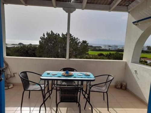 een tafel en stoelen op een patio met uitzicht op de oceaan bij Glyfada Suite in Kastraki Naxou