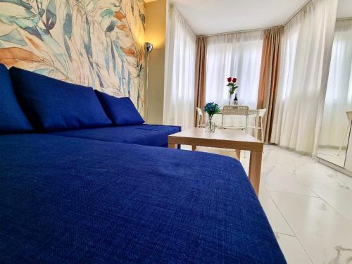 Un dormitorio con una cama azul y una mesa en El Oasis de SteraM Flats Torremolinos, en Torremolinos