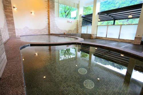 烏來區的住宿－烏來Spring Spa溫泉山莊，水中反射的建筑物中的游泳池