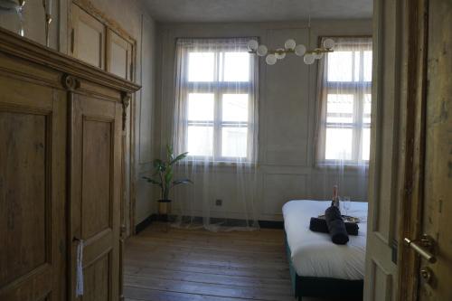 a bedroom with a bed and two windows at Modiste in Kuldīga