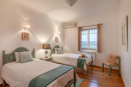 a bedroom with two beds and a window at Quinta da Pinheira Lezíria in Alpiarça