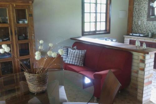 a living room with a red couch and a glass table at Chale no centro de Lumiar com água de nascente in Nova Friburgo