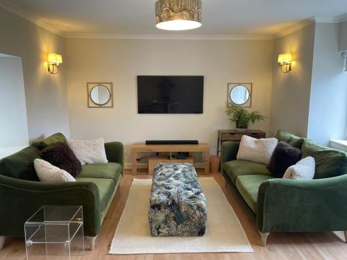 a living room with two green couches and a tv at Smithy House in Tongue