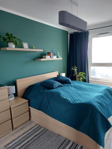 a bedroom with a bed and a blue wall at Apartament przy stadionie in Gdańsk