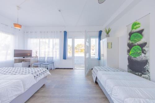 a white bedroom with two beds and a desk at Hôtel Land'Azur in Mimizan-Plage