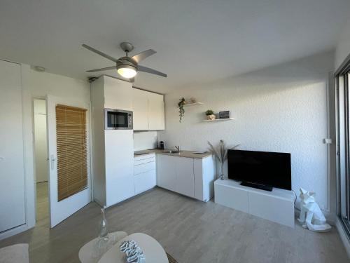 Il comprend une cuisine avec des placards blancs et un ventilateur de plafond. dans l'établissement Blue Sky La Grande Motte Studio -Pool-5min Beach -Queensizebed -WiFi, à La Grande Motte