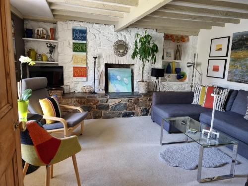 a living room with a blue couch and a stone fireplace at An Artist's Cottage in Fishguard