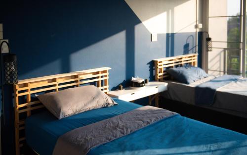a bedroom with two beds and a blue wall at Kaze House in Chiang Rai
