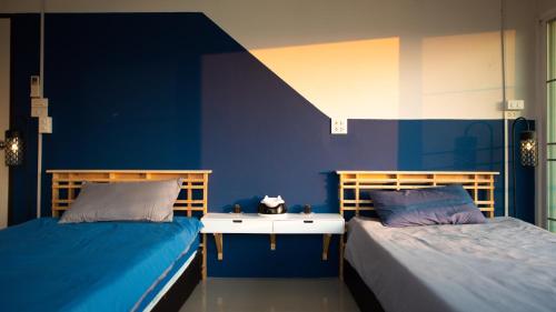 two beds in a room with blue walls at Kaze House in Chiang Rai