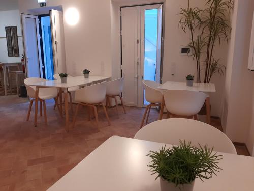 a dining room with white tables and chairs and plants at Casa Algarbe in Faro