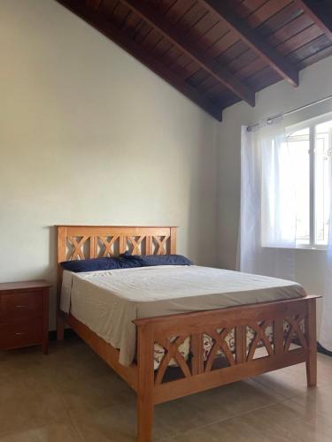 a bedroom with a wooden bed in a room with a window at ‘MORIAH’ Private Room with Double Bed and shared bathroom in Saint Philip