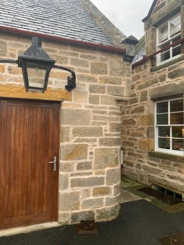 a stone house with a wooden door and a lamp at Kilmorie House in Elgin