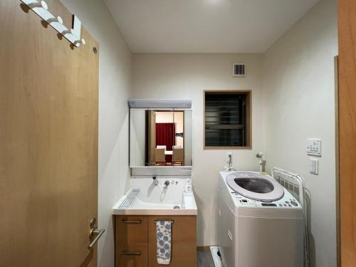Guesthouse Kaede Annex في نارا: حمام مع مغسلة وغسالة ملابس
