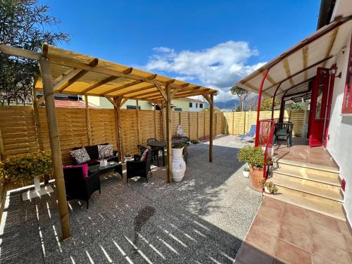 a patio with a wooden pergola and tables and chairs at House Viareggio in Viareggio