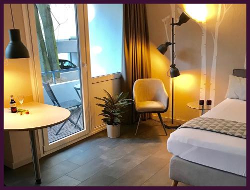 ein Schlafzimmer mit einem Bett, einem Tisch und einem Stuhl in der Unterkunft Apartment EULE - Gute-Nacht-Braunschweig in Braunschweig