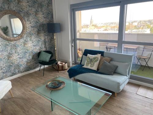 uma sala de estar com um sofá e uma mesa de vidro em Magnifique appartement au coeur de Mulhouse em Mulhouse
