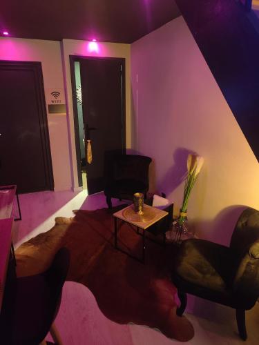 a living room with purple lighting and a table and chairs at La tentation in Berck-sur-Mer