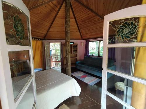 a bedroom with a bed and a couch and windows at Pousada Alquimia in Aiuruoca