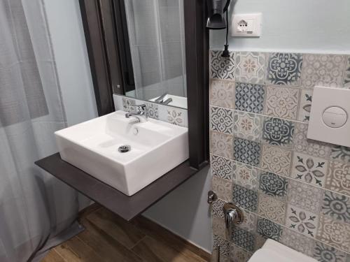 een badkamer met een witte wastafel en een spiegel bij mamarita in Sambuca di Sicilia