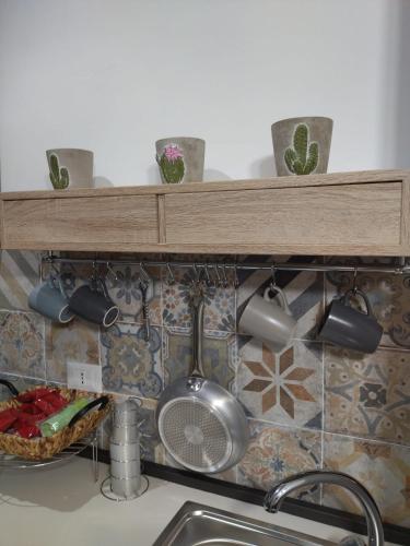 a shelf above a kitchen sink with pots and pans at mamarita in Sambuca di Sicilia