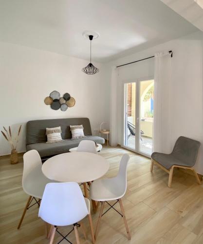- un salon avec une table, des chaises et un canapé dans l'établissement Batsi Seaside Apartment, à Batsi