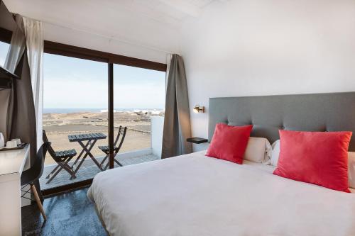 a bedroom with a large bed with red pillows at Casa De La Nobleza in Tinajo