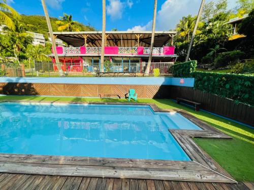a swimming pool with a house in the background at Le Nid Tropical in Bouillante