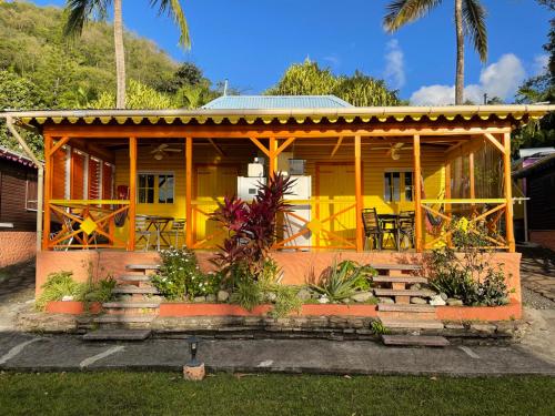 a yellow house with a table and chairs at Le Nid Tropical in Bouillante