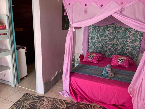 a pink bed with pink pillows and a canopy at Le Nid Tropical in Bouillante