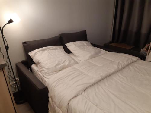 a bed with white sheets and pillows on it at Studio au cœur des Volcans d Auvergne - Murol in Murol