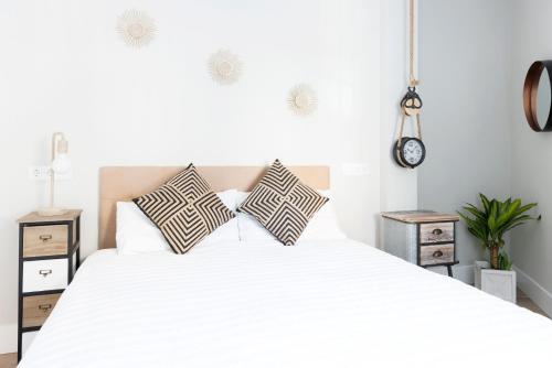 - une chambre avec un grand lit blanc et des oreillers dans l'établissement Apartamento Deluxe El Avión, à Alcalá de Henares