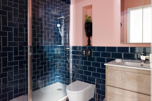 a blue tiled bathroom with a toilet and a sink at Apartamento Deluxe El Avión in Alcalá de Henares