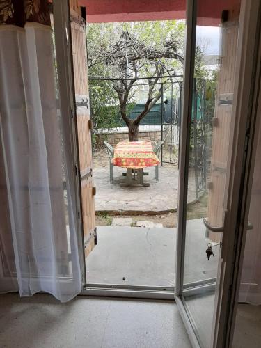 Une porte ouverte s'ouvre sur une terrasse avec une table à l'extérieur. dans l'établissement Grand studio confort, à Nîmes