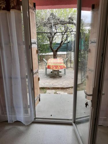 eine offene Tür zu einer Terrasse mit einem Tisch im Freien in der Unterkunft Grand studio confort in Nîmes