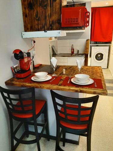 eine Küche mit einer Theke mit 2 Stühlen und einem Tisch in der Unterkunft Grand studio confort in Nîmes