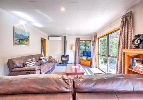 a living room with leather couches and a tv at 7b Denby Place in Hanmer Springs