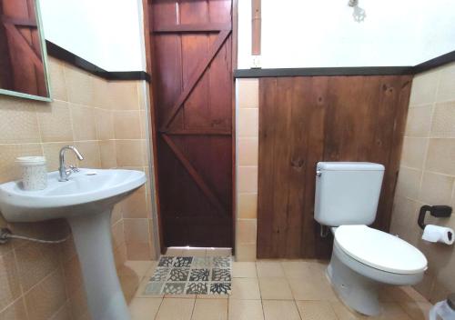 a bathroom with a toilet and a sink and a door at La Bella Fiore in São Roque