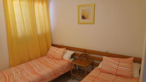 a room with two beds and a chair and a picture at PRECIOSO APARTAMENTO AL LADO DE BONITA CALA in Ciutadella