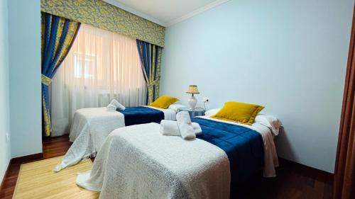 two beds in a room with blue walls at Piso Céntrico Nati Con Parking Incluído in O Grove
