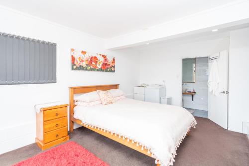 biała sypialnia z łóżkiem i komodą w obiekcie Apartment on Robert Rd w mieście Raglan
