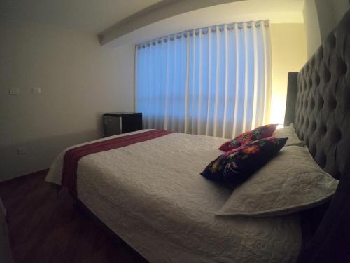 a bedroom with a bed with two pillows and a window at Residencial Chávez Concha / Cusco in Cusco