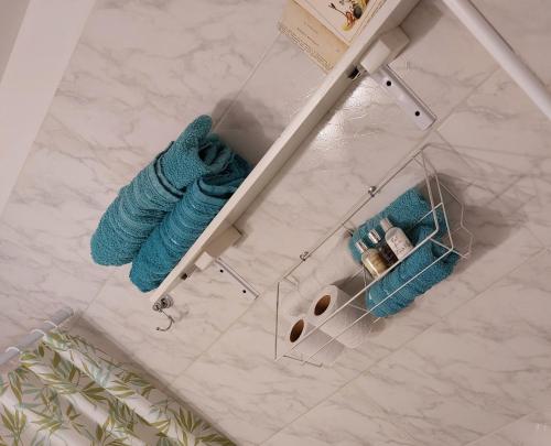 a bathroom with two blue towels on a shelf at Calido,moderno depto con piscina, parking ,laundry in Remedios de Escalada