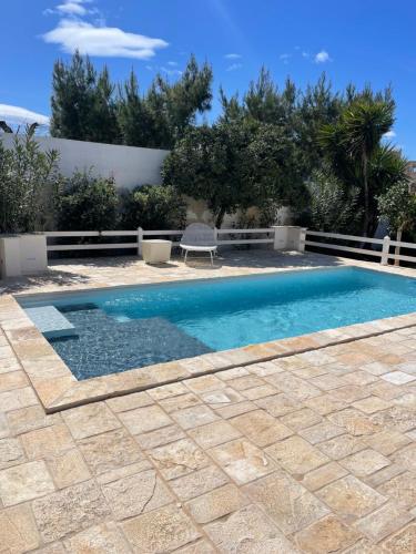 una piscina con una silla junto a una casa en Sine tempore beach holiday home, en Maruggio