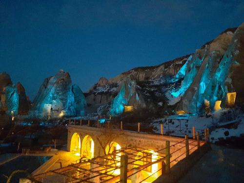 - une vue nocturne sur un hôtel de glace aux lumières bleues dans l'établissement Seven Rock Cave Hotel, à Gorëme