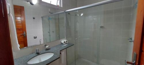 a bathroom with a sink and a shower with a mirror at Praia Boulevard Flat Porto Bahia in Porto Seguro
