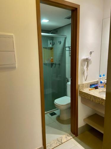 a bathroom with a toilet and a glass shower at Olímpia Park Resort Apto in Olímpia