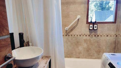 a bathroom with a sink and a tub with a window at Casa con jardín y cochera ¡A 5 minutos del lago! in San Carlos de Bariloche