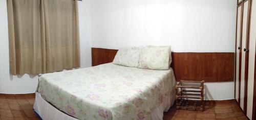 ein Schlafzimmer mit einem Bett und einem Stuhl darin in der Unterkunft Apê da Mi - 2 min da Praia de Pitangueiras - Guarujá in Guarujá