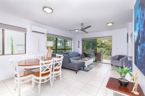 a living room with a table and chairs at Seascape Holidays - Tropical Reef Apartments in Port Douglas